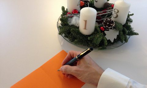 Foto: Adventskranz und schreibende Hand